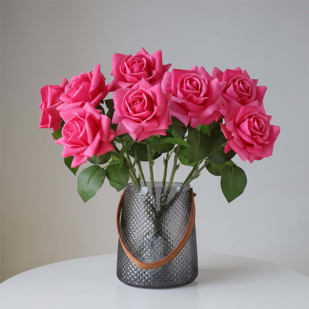 Bouquet of pink roses in a textured vase on a white surface with a neutral background
